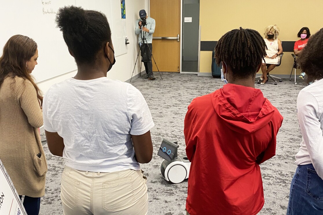 An image of Amazon's Greene Scholars Program participants with an Amazon Astro robot.