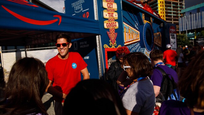 一个穿着红色t恤和太阳镜在宝工作的卡车,分发独家交易别针运动员在闭幕式上。宝卡车周围是人们穿着特殊奥林匹克运动会和小礼品。