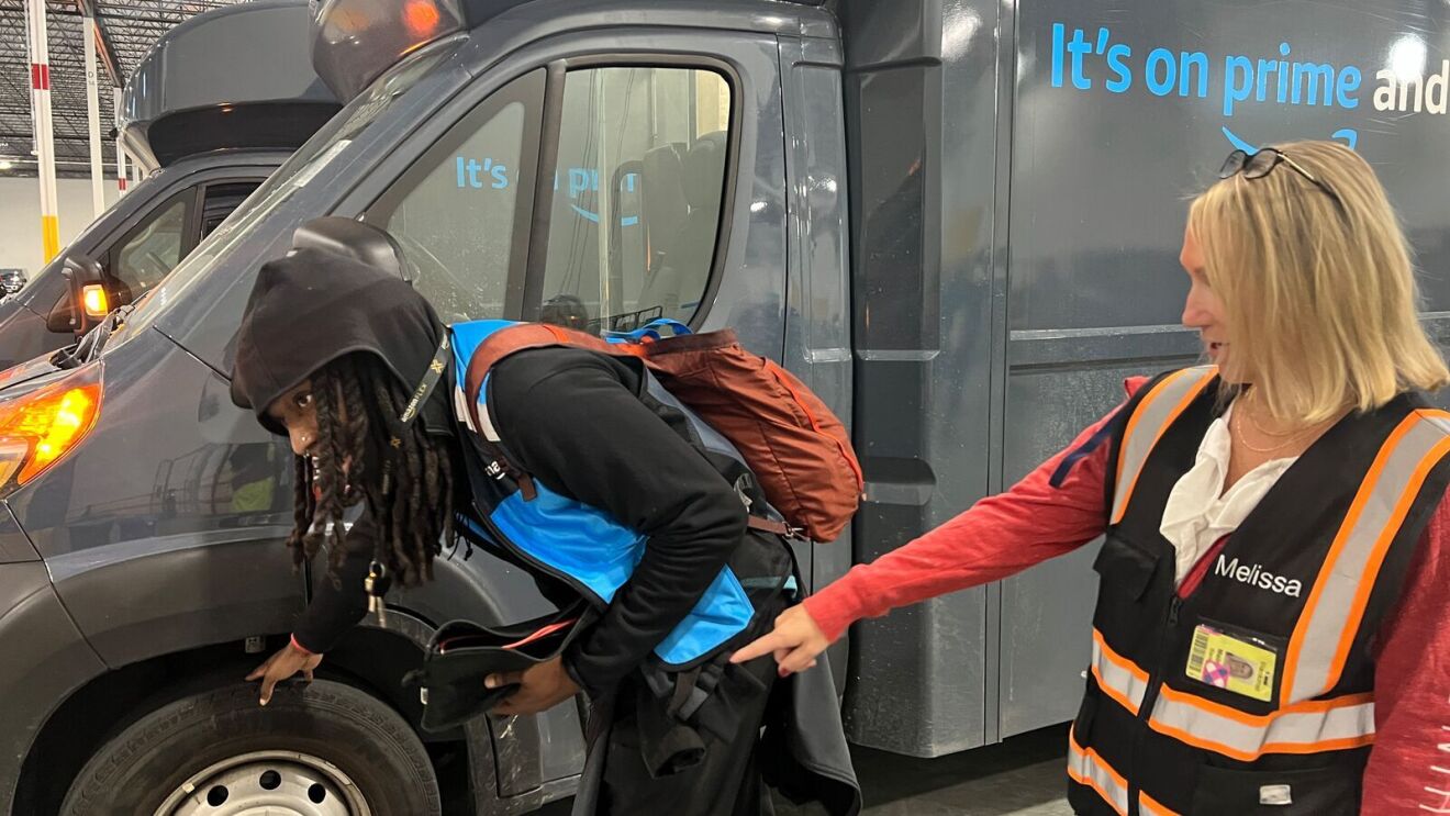 An image of a woman, an Amazon Delivery Service Partner, in a work vest standing in front of a delivery van.