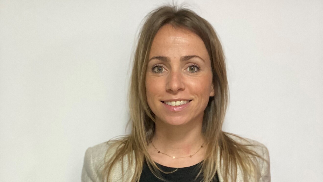 Ana Cruz Dorado, responsable de Recursos Humanos en SVQ1 (centro logístico de Amazon Robotics en Sevilla). Con una jersey negro y una americana gris. Se aprecian unos jeans. El pelo rubio por el hombro y los ojos verdes. Lleva una cadena de oro con estrellas.