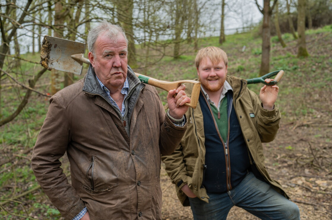 Jeremy Clarkson and Kaleb Cooper standing in the woods holding shovels 