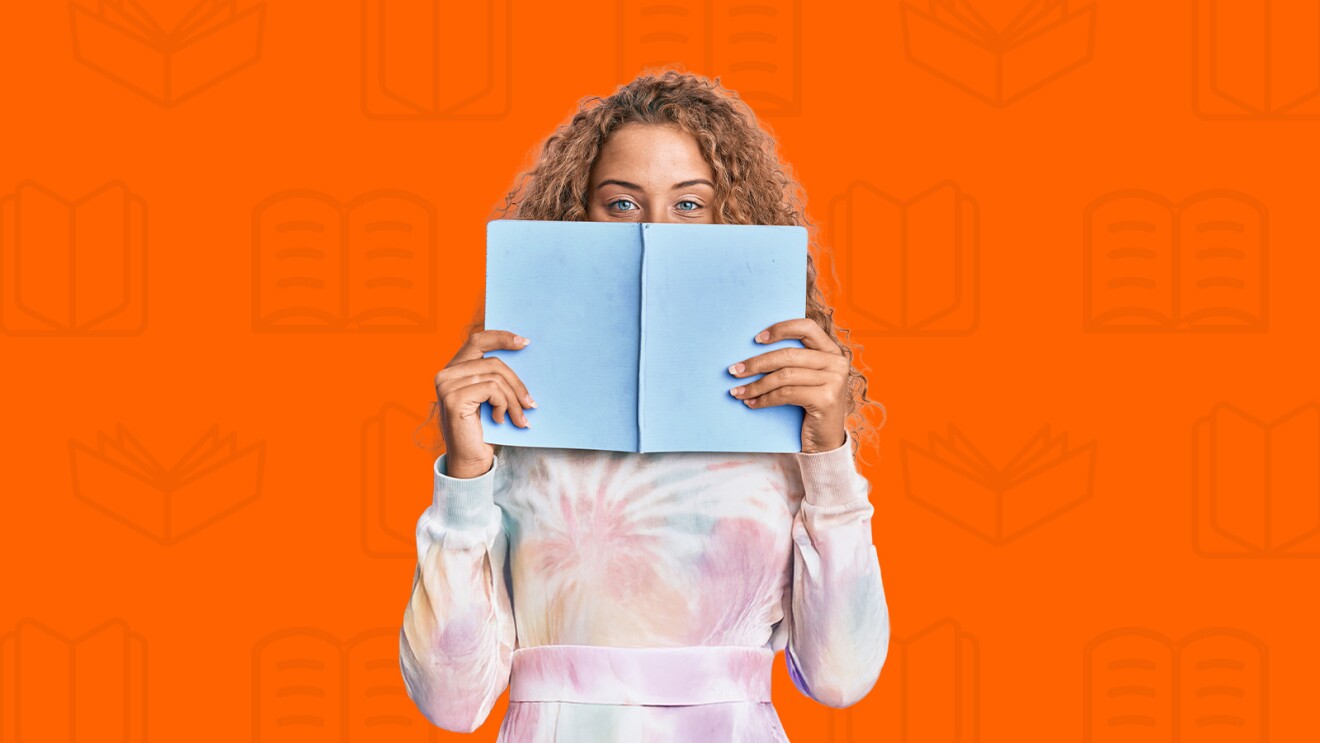 Curly-haired person holding open book in front of face against orange background