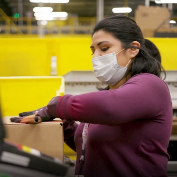 Amazon employee performing work duties while wearing a mask, during COVID-19 pandemic.