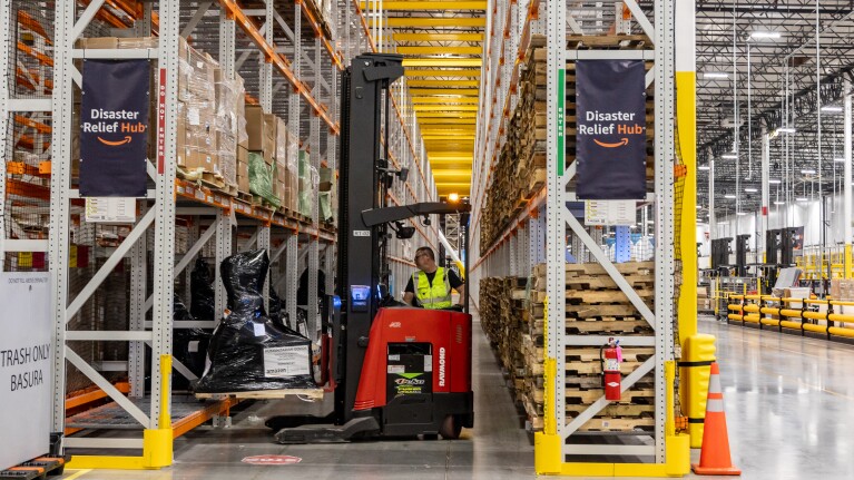 Wildfire disaster relief hub: Warehouse worker operating forklift in Amazon Disaster Relief Hub