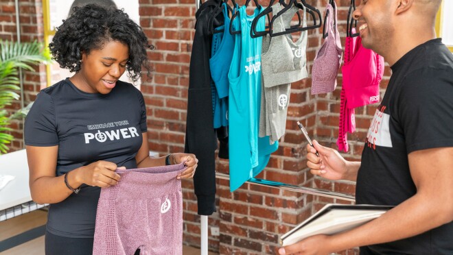 天使举起一双ICONI紧身裤时一个人持有纸和笔在她的微笑。