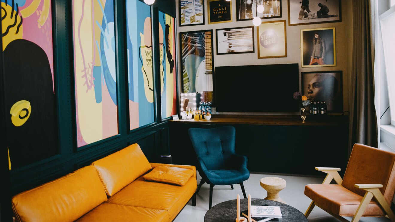 An image of a living room space with jewel ton furniture and colorful art on the walls.