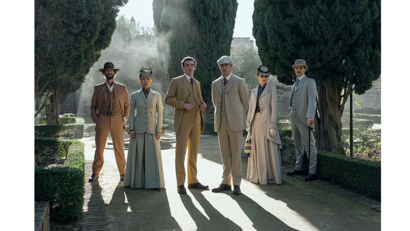 好演のような屋外で、スーツを着て並ぶ6人の人物。