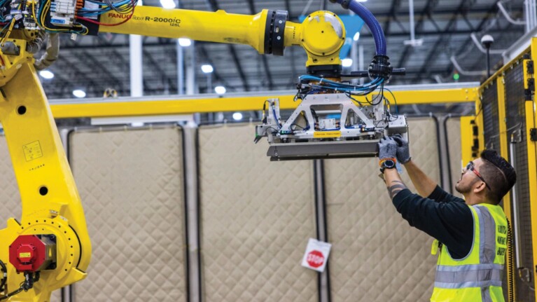 A photo of an Amazon employee working on a robot in a fulfillment center.