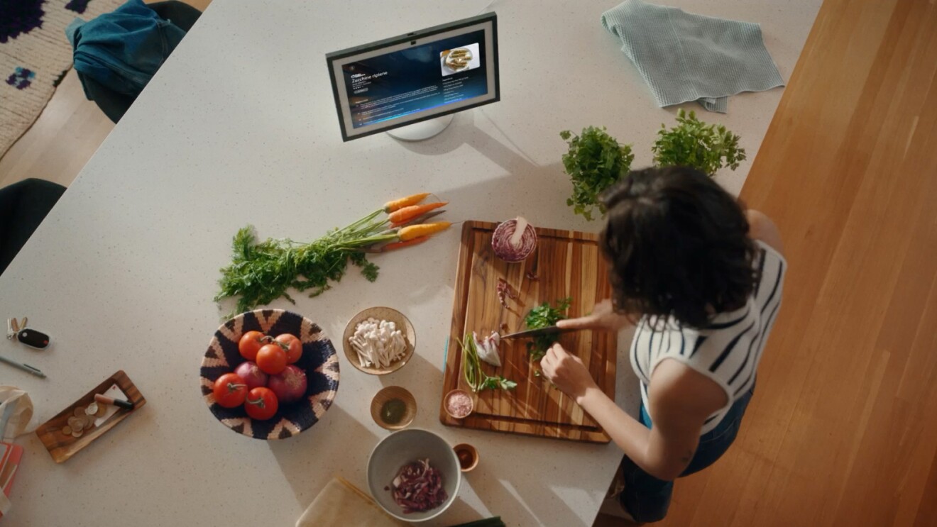Overhead shot of a woman preparing food at a kitchen counter with her Alex+ connected device.