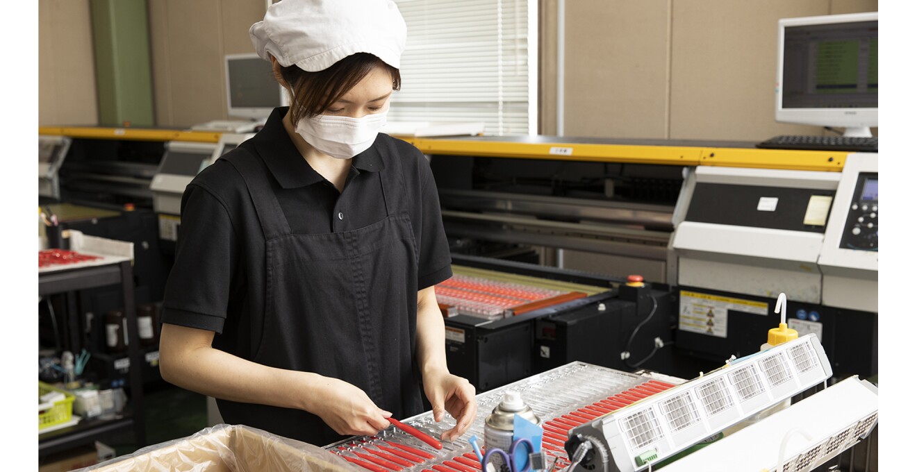 製造中の写真。スタッフの後ろに大きな機械がある。