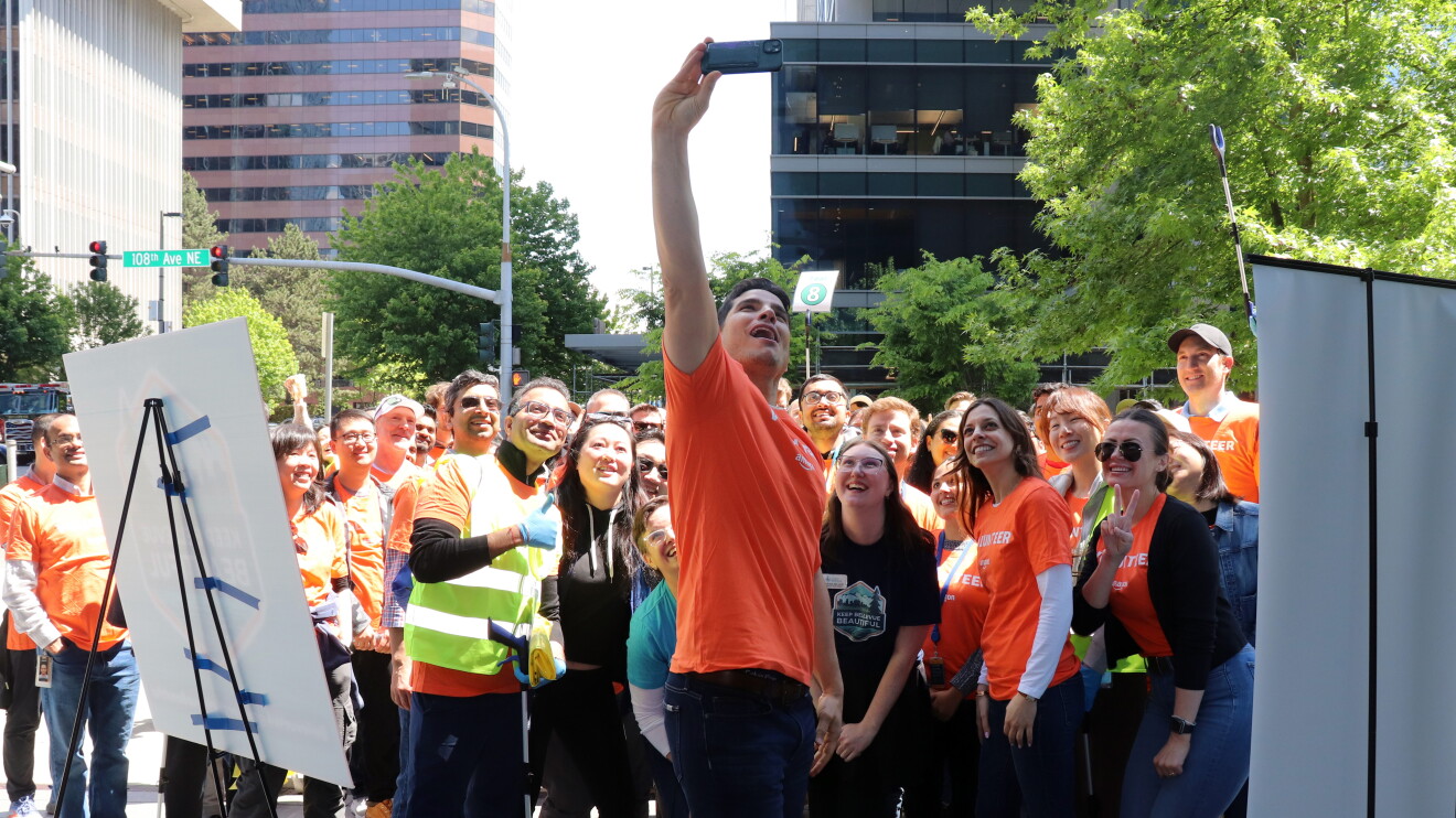 Large group in orange shirts taking selfie and gathered for community service day in downtown area