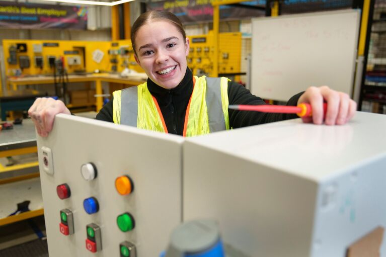 A girl smiling whilst holding open a door