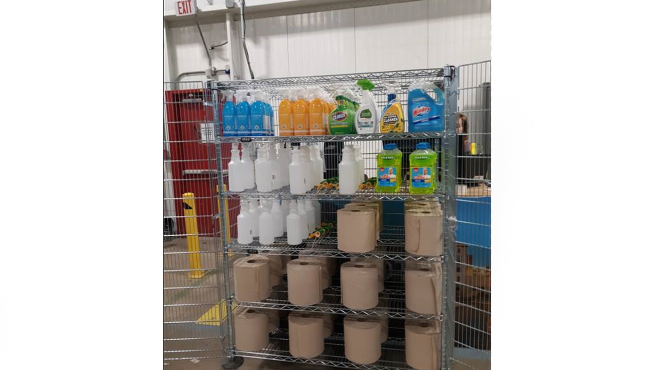 Metalowy stojak na ręczniki papierowe i środki czyszczące wewnątrz centrum realizacji Amazon, do użytku przez współpracowników w pracy.