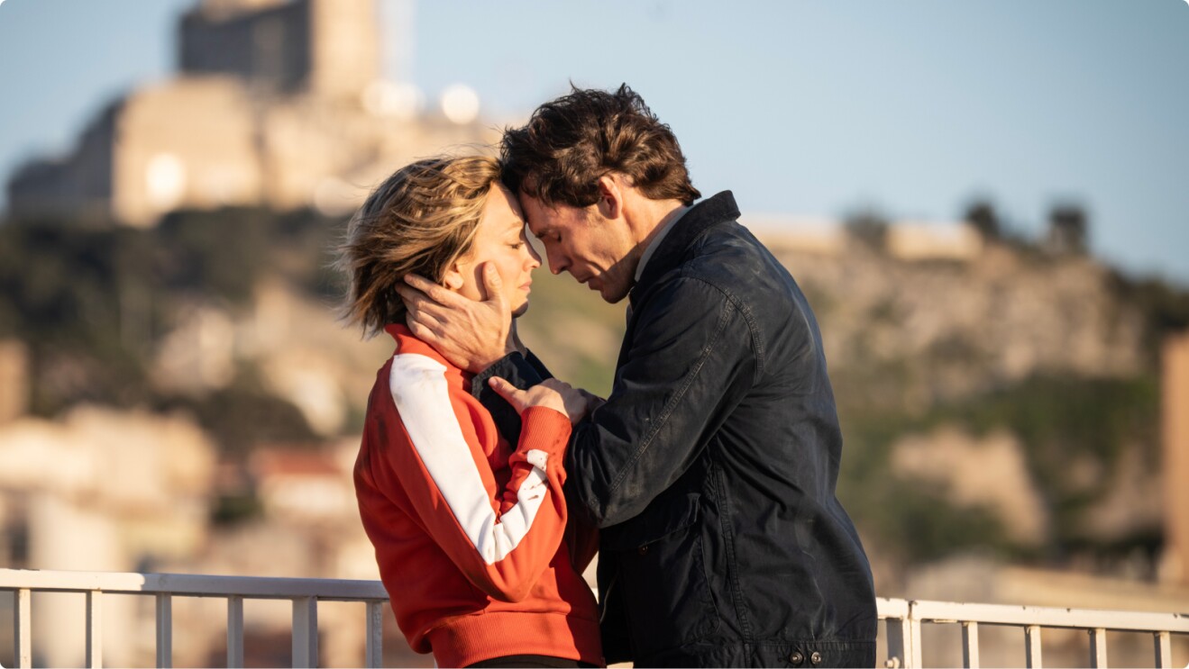 Vanished starring Kaley Cuoco and Sam Claflin, who hold each other close on a sunny balcony.