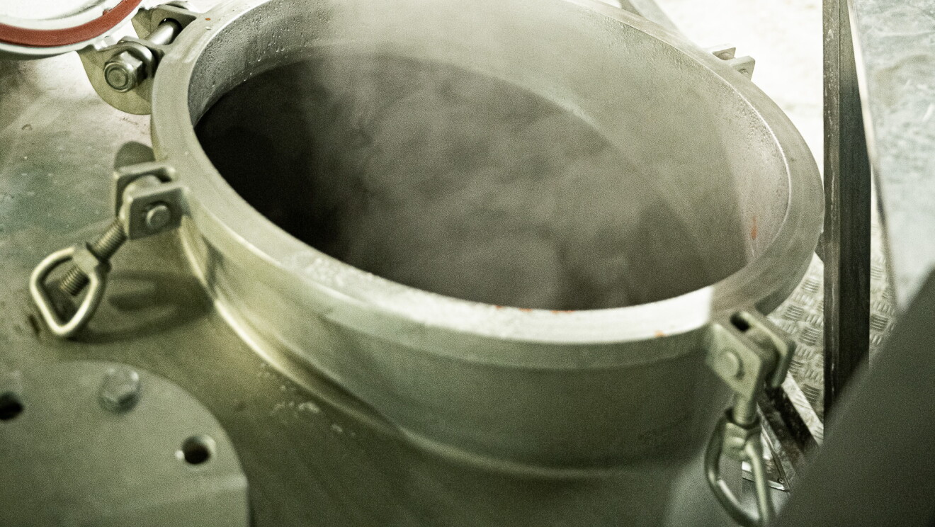 Primer plano de la producción de la salsa Espicy. En la fábrica hay un recipiente metálico del que sale humo. 
