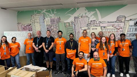 A group of Amazon employees take a break from packing back to school backpacks for children