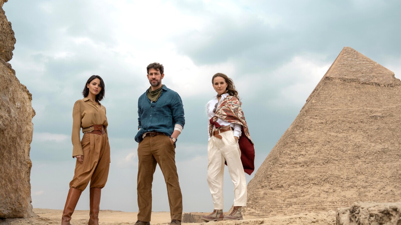 A group of adventurers standing on desert rocks near ancient Egyptian pyramid in the Fountain of Youth on Prime Video