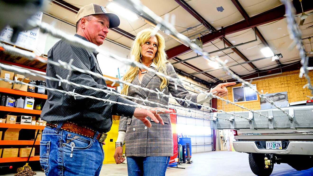 A photo of two people inspecting barbed wire in a workshop.