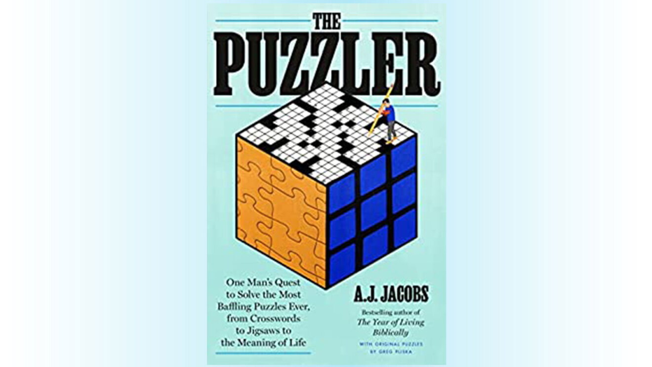 A photo of the book cover, "The Puzzler: One Man's Quest to Solve the Most Baffling Puzzles Ever, from Crosswords to Jigsaws to the Meaning of Life". The cover features a cube the top of the cube has an illustration of a crossword puzzle. The left side of the cube features a traditional cut out puzzle. The right side of the cube features a grid.