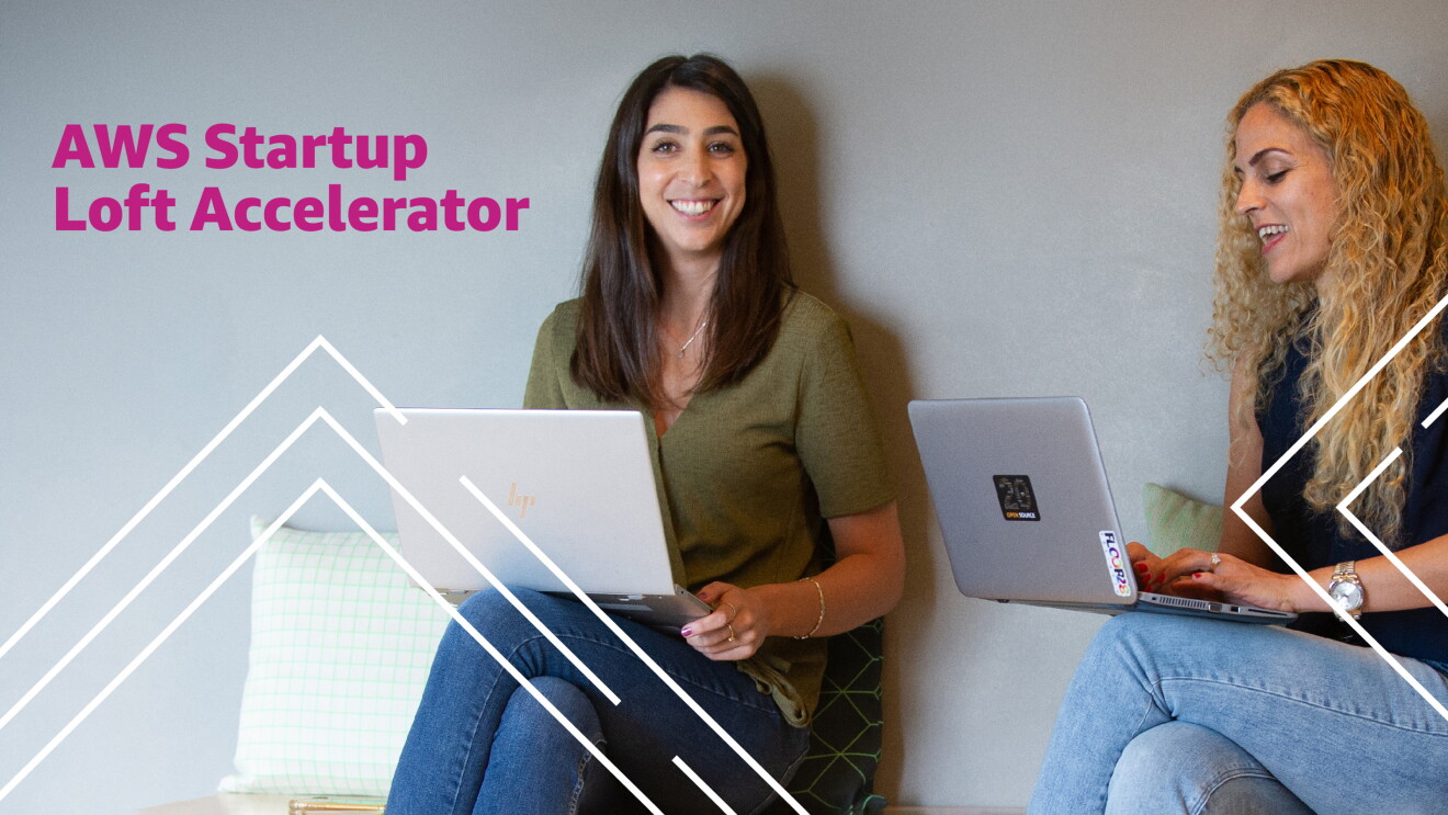 Two women in a shared workspace, working on their laptop computers. 