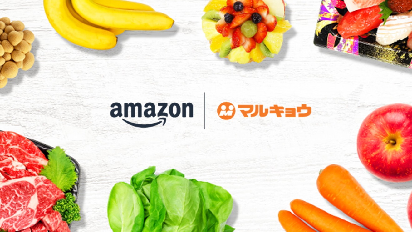 白と薄いグレーの木目調の背景、中央にAmazonとマルキョウのロゴが横並びに配置。ロゴの周りは肉のパック、キノコ、バナナ、フルーツサラダ、寿司のパック、リンゴ、ニンジン、レタスが取り囲む。