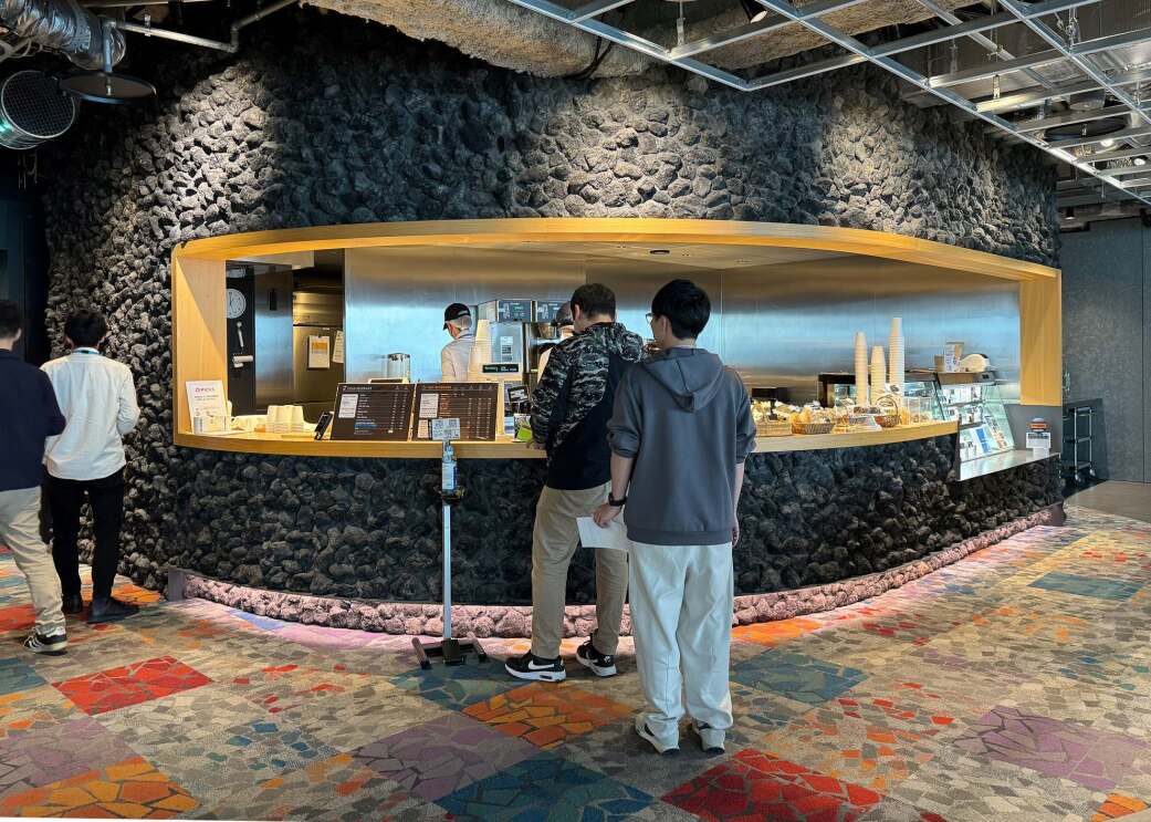 ゆるくカーブした黒い岩のような壁面をくりぬいたようなカウンターに並ぶ人たち