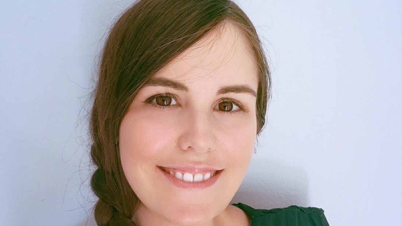 Elisabeth Llamas en plano medio de su cara, hasta el pecho. Lleva una trenza en el pelo de color castaño que no se le su final. Un vestido de tirantes anchos de color verde. Mira a cámara sonriendo. Tiene los ojos marrones. 