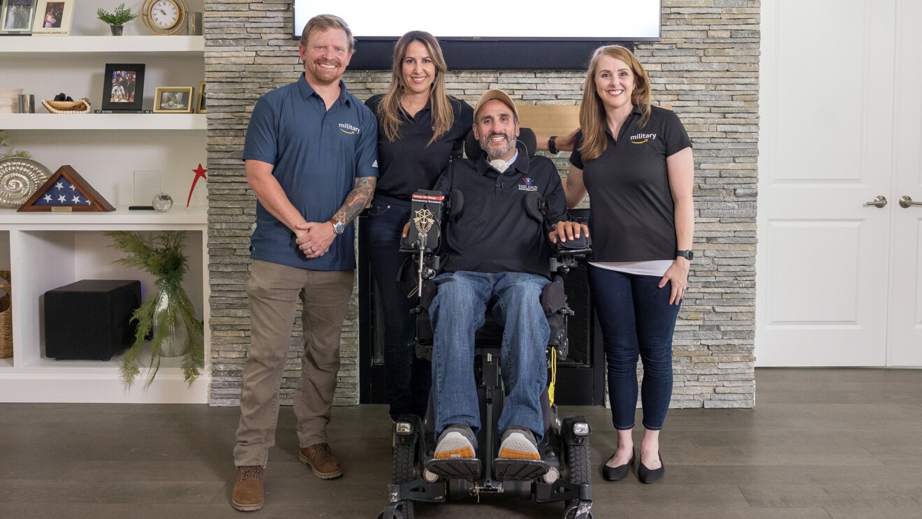 Matthew Williams, senior program manager on Amazon’s Global Military Affairs team, standing next to with veteran Romy Camargo and his wife, and his colleague, Charlotte La Belle, in Camargo's specially adapted smart home.