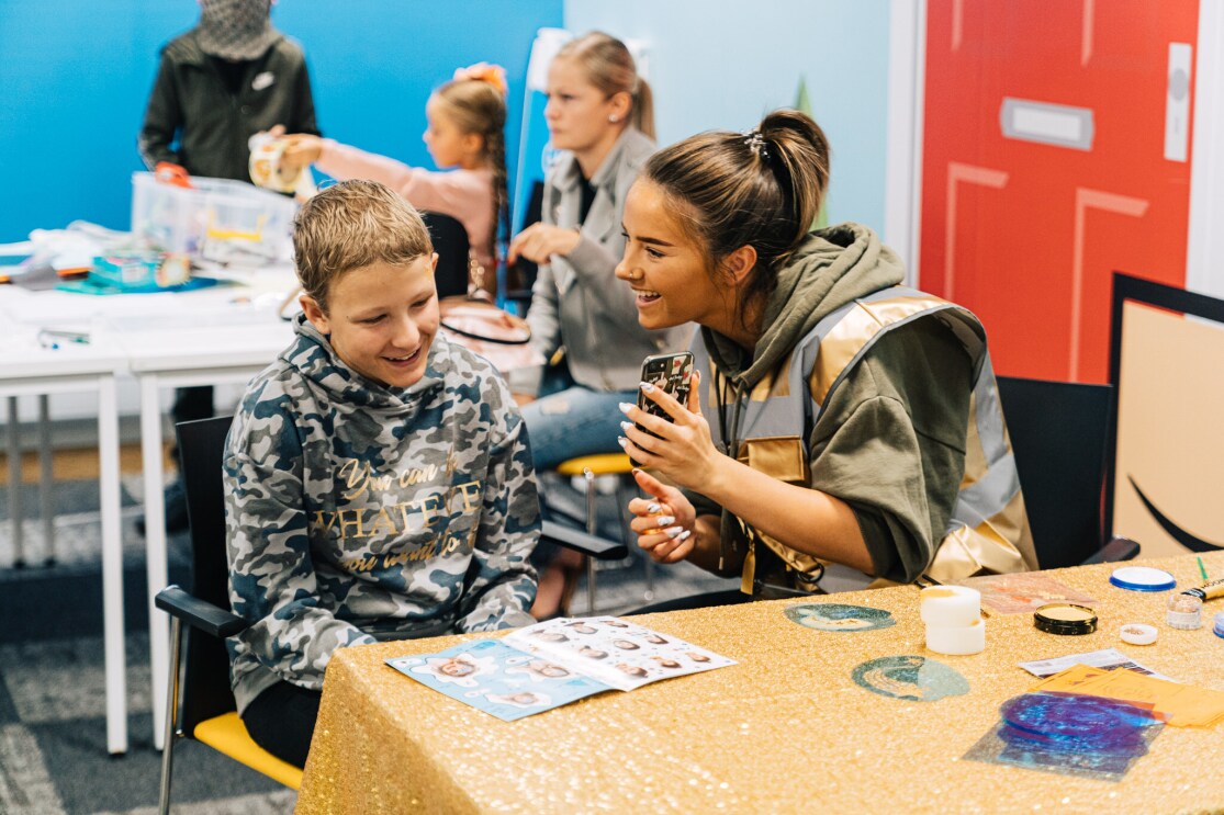 A child and an Amazon employee smiling and playing together at a STEM camp