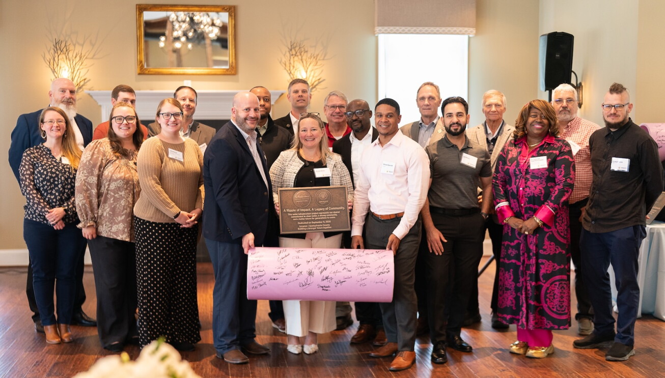 Amazon and Spotsylvania County leaders posing with a signed purple pipe at a ceremonial event celebrating the start of construction on a new water reuse system