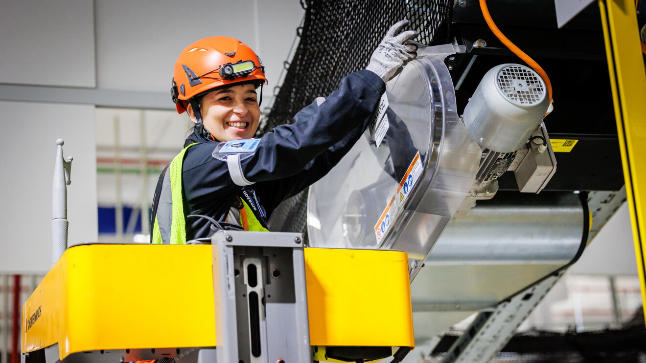 Mujer trabajando arreglando una máquina dentro de un centro logístico. 
