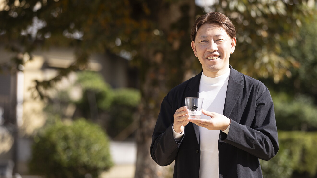 グラスを手に持ちほほ笑むジャケットを着た男性