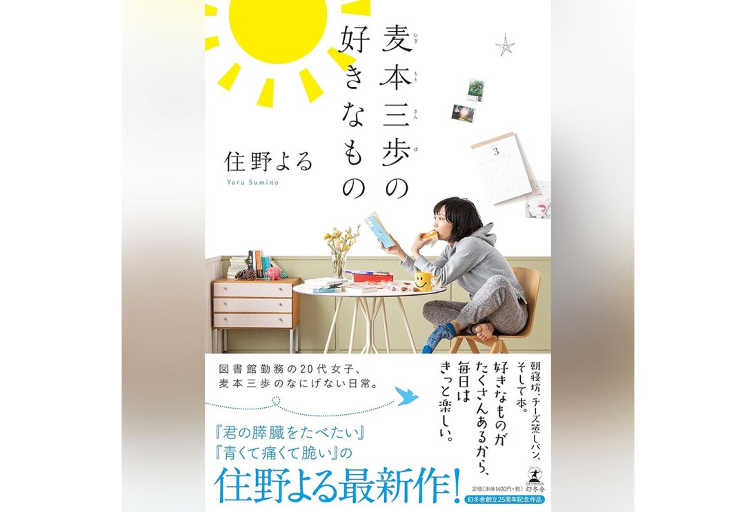 グラデーション背景に縦長の書籍表紙。下側に帯がかかっている。帯の上に見える表紙は、白い壁の部屋でテーブルに向って椅子に胡坐をかき、本を読みながら何かを食べる女性。中央に「麦本散歩の好きなもの」の字。