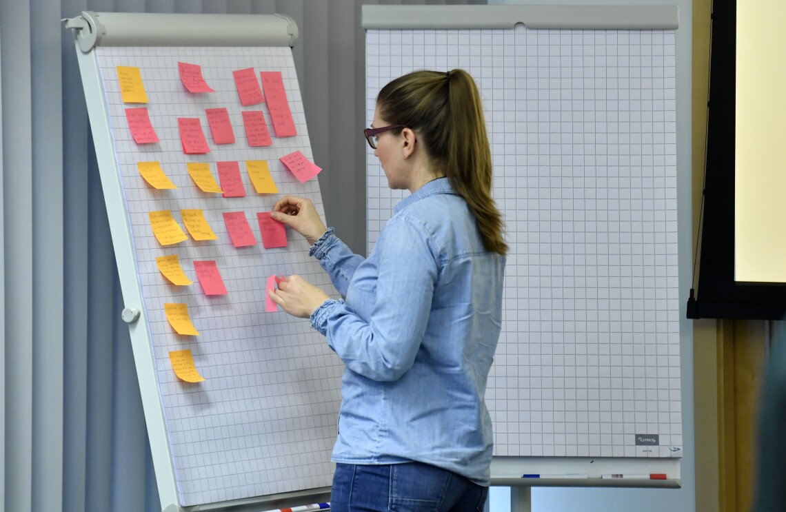 Eine Teilnehmerin steht an einem Flipchart und klebt Post-its auf
