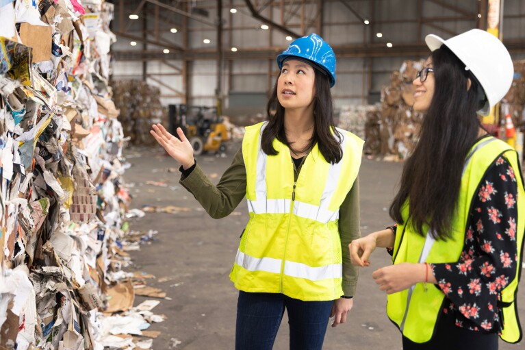 Two women stand at a recycling centre
