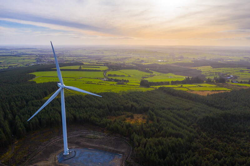 A wind turbine, from an Amazon wind farm, in front of fields in Europe. 