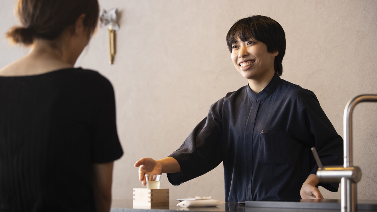 カウンターで日本酒を差し出すスタッフ