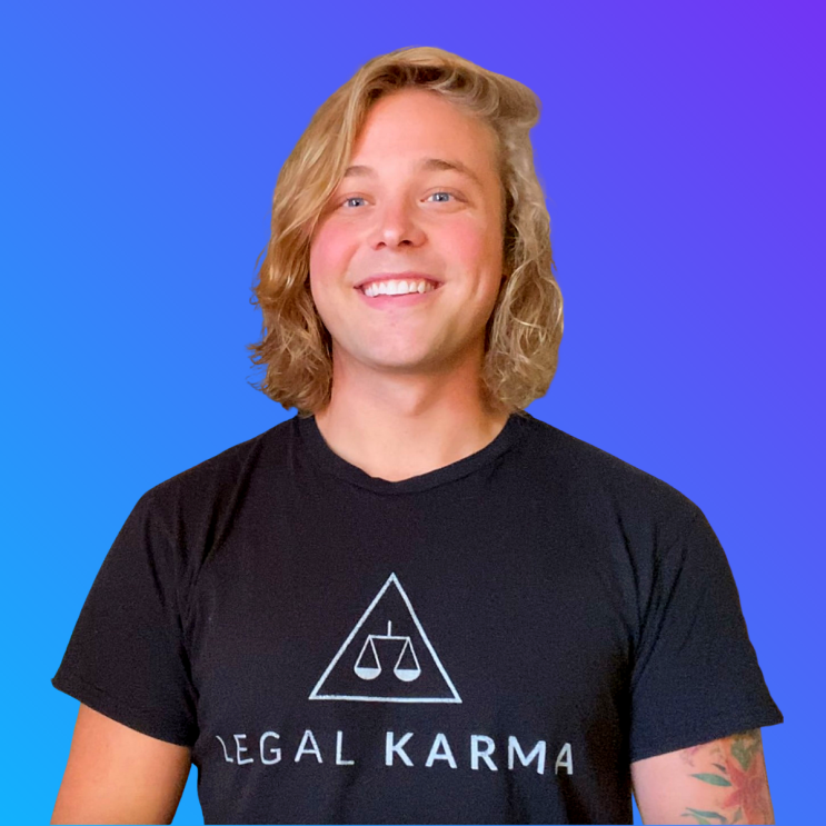 A headshot image of Kory Kelly wearing a shirt that says "Legal Karma" and smiling for a the photo in front of a blue background.