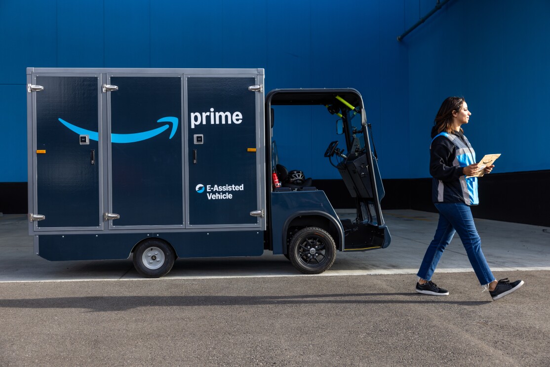 An Amazon delivery driver walks in front of the new e-cargo bikes.