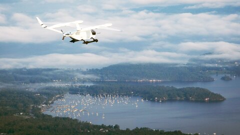 小型飞机飞过水和土地部分多云的天空