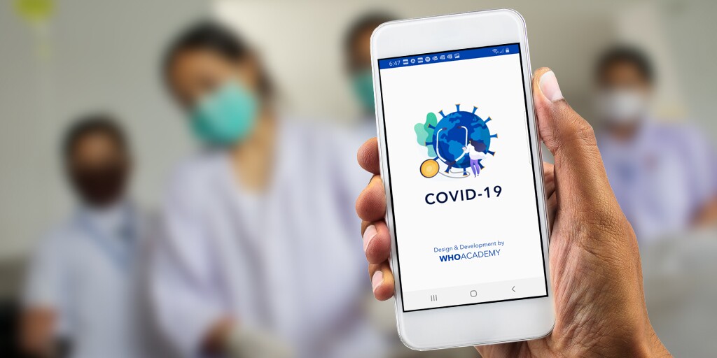 World Health Organization Academy app on a mobile phone, held in a patient's hand with four medical personnel blurred out in the background. 