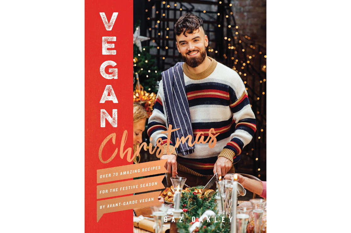 Vegan Christmas cookbook features a man wearing a sweater, with a dish towel thrown over his shoulder, carving into a dish. On either side of him are guests at his table, appearing to enjoy a holiday meal.