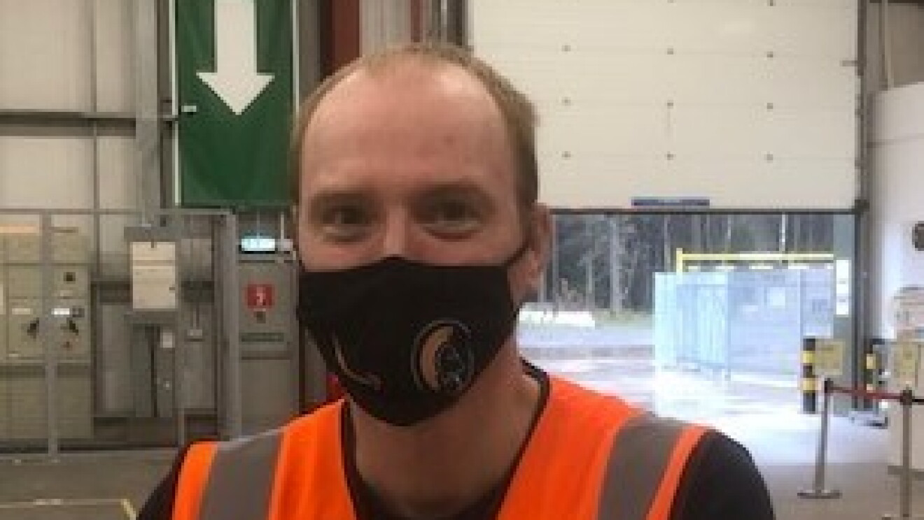 Alex Van Krimpen, temporary operations supervisor at Amazon's delivery station in Penrith pictured on the shop floor wearing a high visibility vest and a black face mask.