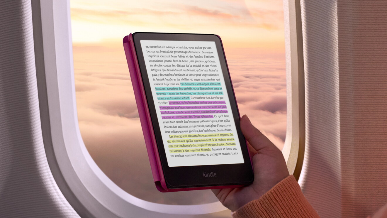 Une main tenant un Kindle Colorsoft pour lire dans l'avion