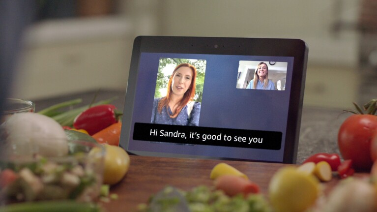 An image of an Echo Show device with people who are on a call together. There are captions at the bottom of the screen.