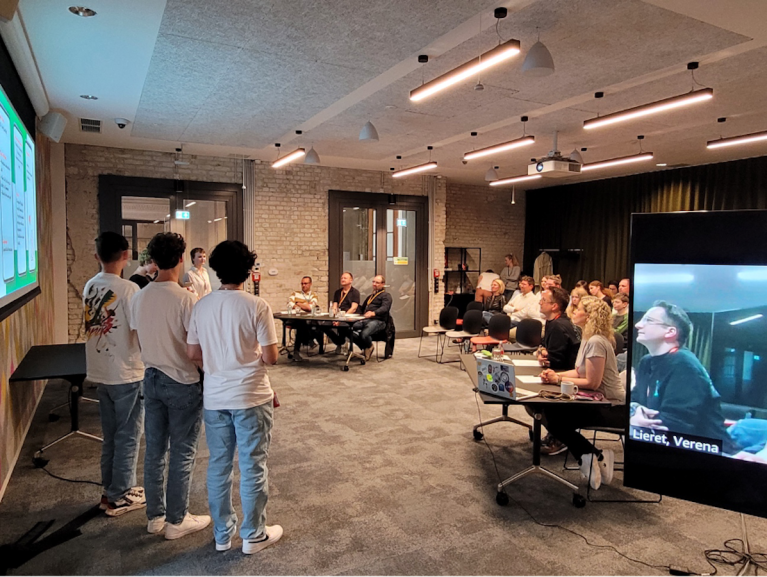 AWS Juroren hören zu, als ein Team seine App-Idee präsentiert.