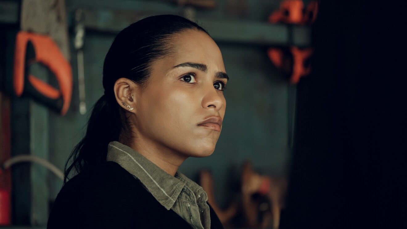 A young woman with black hair looks ahead angrily