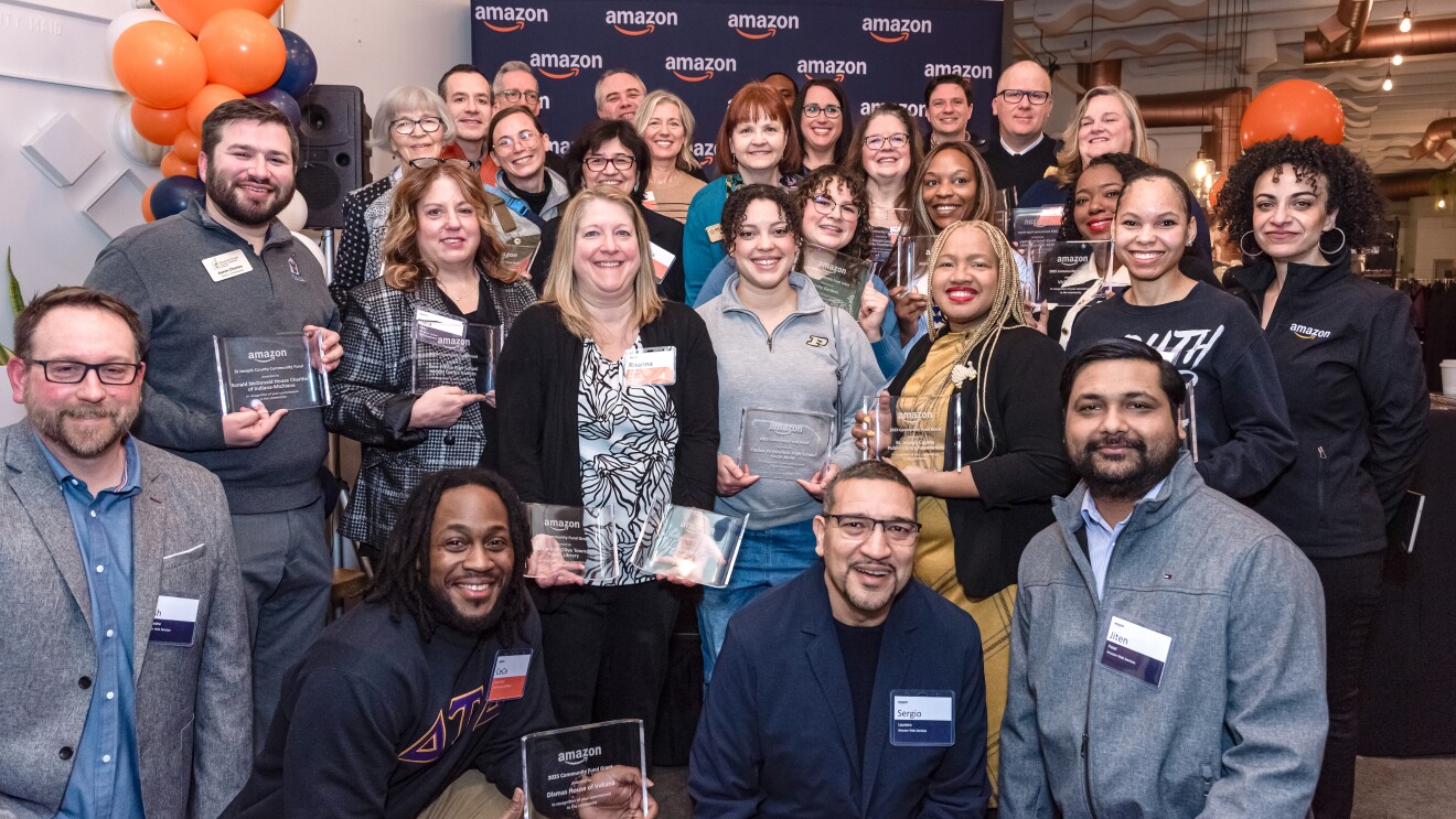 individuals holding an award with amazon in the background, diverse group