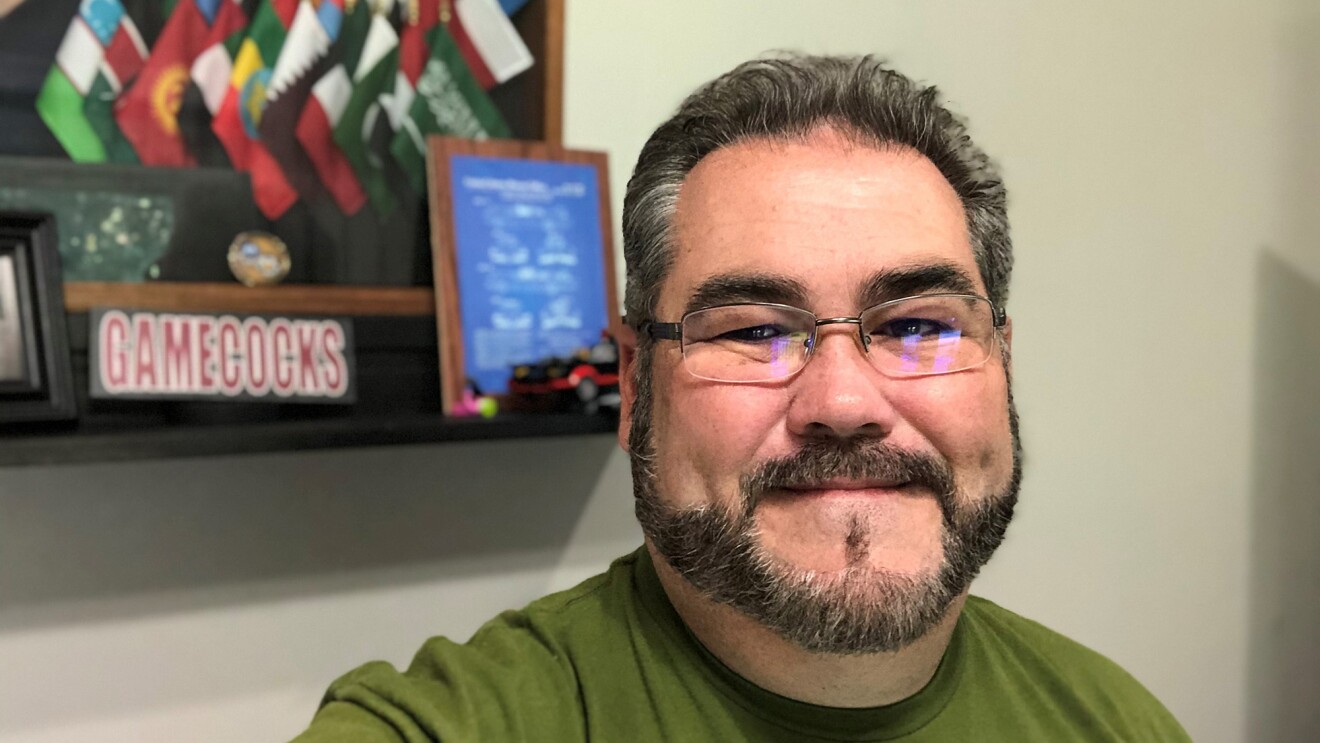 An image of a man smiling for a selfie photo in his home.