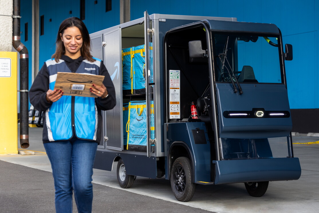 An Amazon delivery driver walks away from an e-cargo bike with a package.